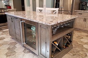 Granite topped island with built in wine storage and rustic grey cabinetry