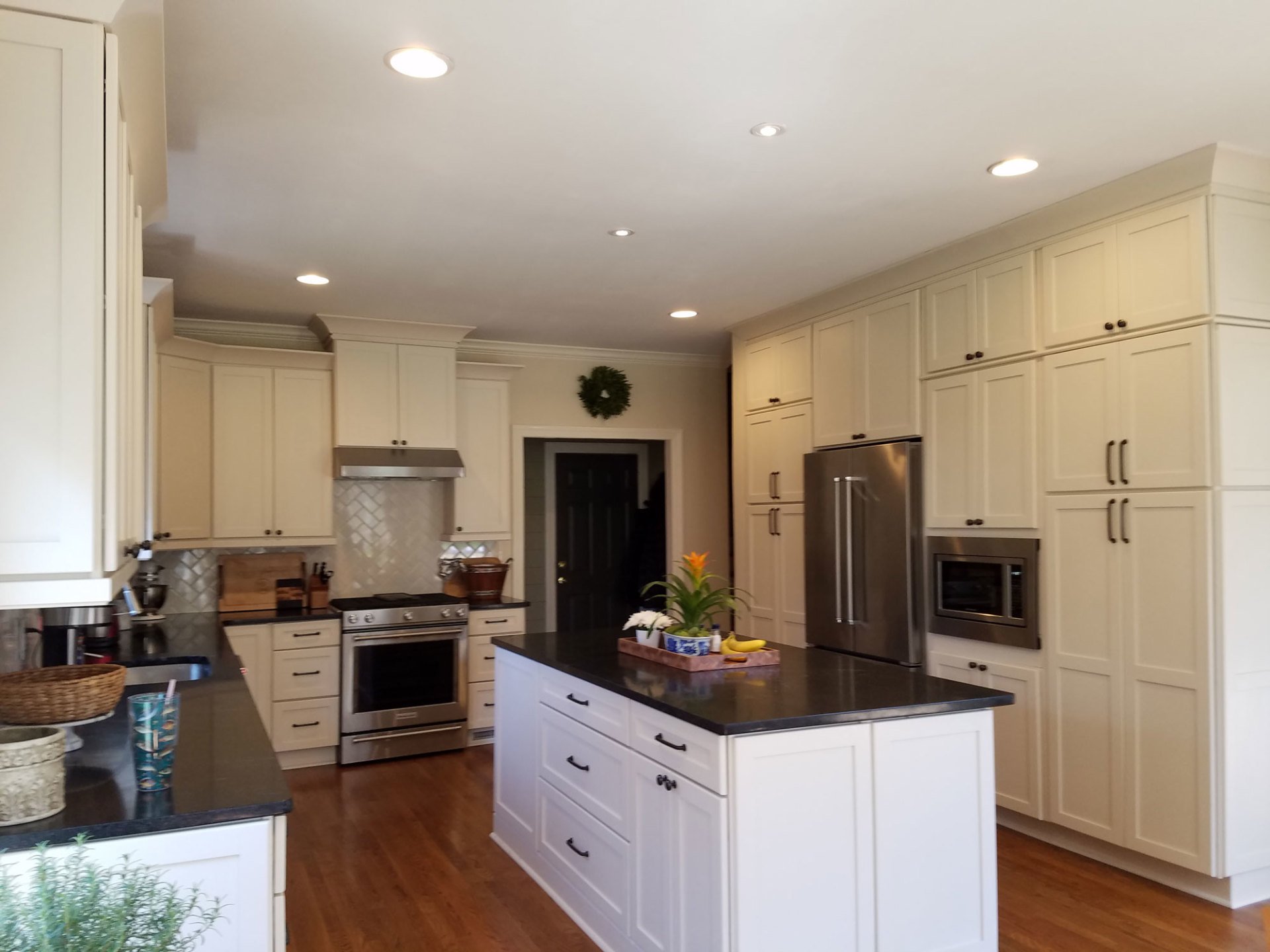 Cream painted kitchen with floor to ceiling cabinetry, dark granite worktops and a white island